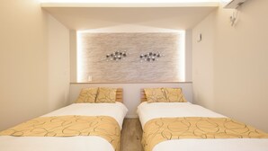 Een hotelkamer met twee bedden, een raam met een lamp en een kunstwerk aan de muur.