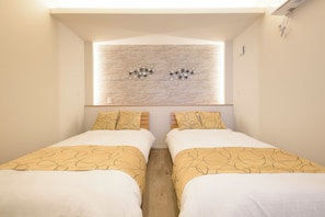 Habitación de hotel con dos camas, una ventana con lámpara y una obra de arte colgada en la pared.