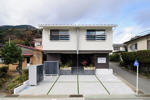 Un edificio de dos pisos con techo plano, ventanas amplias y un cartel.