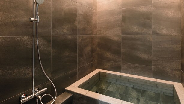 Uma casa de banho moderna com uma banheira independente, um chuveiro manual e um painel de controlo fixado na parede.