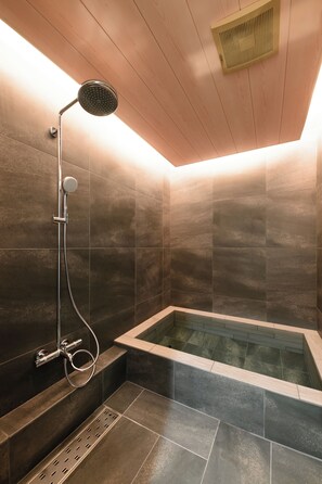 Une salle de bain moderne dotée d’une baignoire sur pied, d’un pommeau de douche à main et d’un panneau de commande fixé au mur.