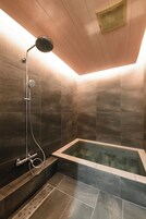 Un baño moderno con una bañera independiente, un cabezal de ducha manual y un panel de control en la pared.