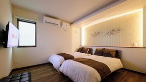 Quarto de hotel com duas camas, uma televisão de tela plana na parede e piso de madeira.