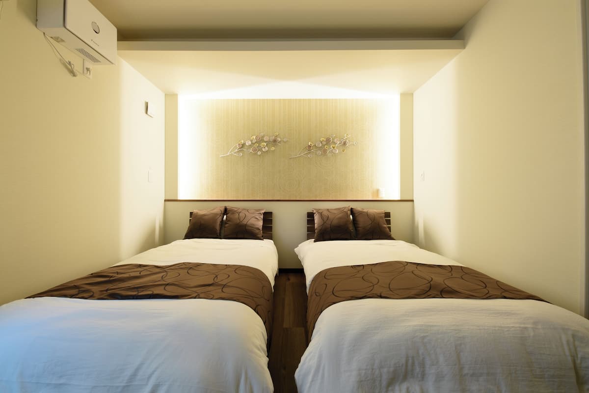 Une chambre d’hôtel avec deux lits, un climatiseur fixé au mur et un panneau décoratif mural.