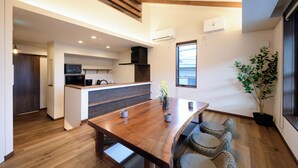 Cozinha moderna com vigas de madeira, área de refeições com mesa e cadeiras de madeira e uma planta em vaso.