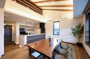 Una cocina moderna con vigas de madera, un comedor con mesa y sillas de madera, y una planta en maceta.