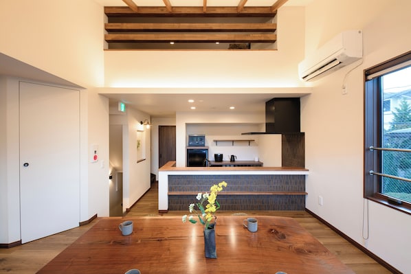 Una cocina moderna con una isla de madera, una zona de comedor con mesa de madera y vistas al exterior a través de un ventanal.