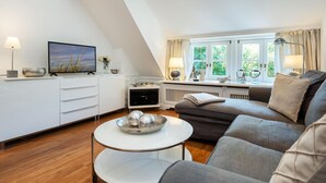 Uma sala de estar moderna com sofá, TV, mesa de centro e área de jantar com mesa e cadeiras.