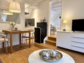 Eine moderne Küche mit Essbereich, einem Fernseher und einer Treppe, die zu einem Schlafzimmer führt.
