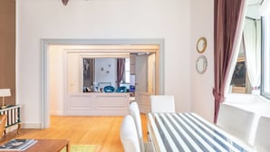 A modern living room with a striped table, a wooden coffee table, and a view into the dining area. - Welcome to Colosseum Haven Steps from Roman Forum (Roma)