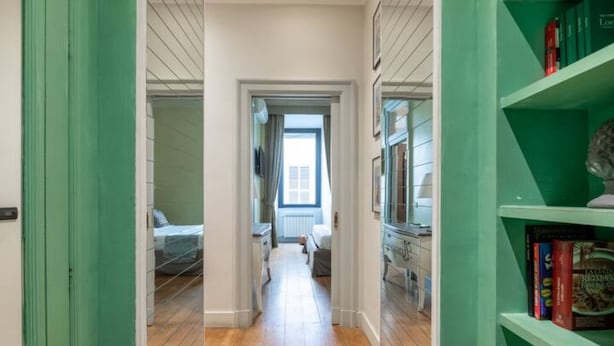 A hallway with wooden flooring, a door on the left, and a bookshelf on the right. - Welcome to Colosseum Haven Steps from Roman Forum (Roma)