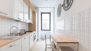 A modern kitchen with white cabinets, a wooden countertop, a sink, and a window with blinds. - Welcome to Colosseum Haven Steps from Roman Forum (Roma)