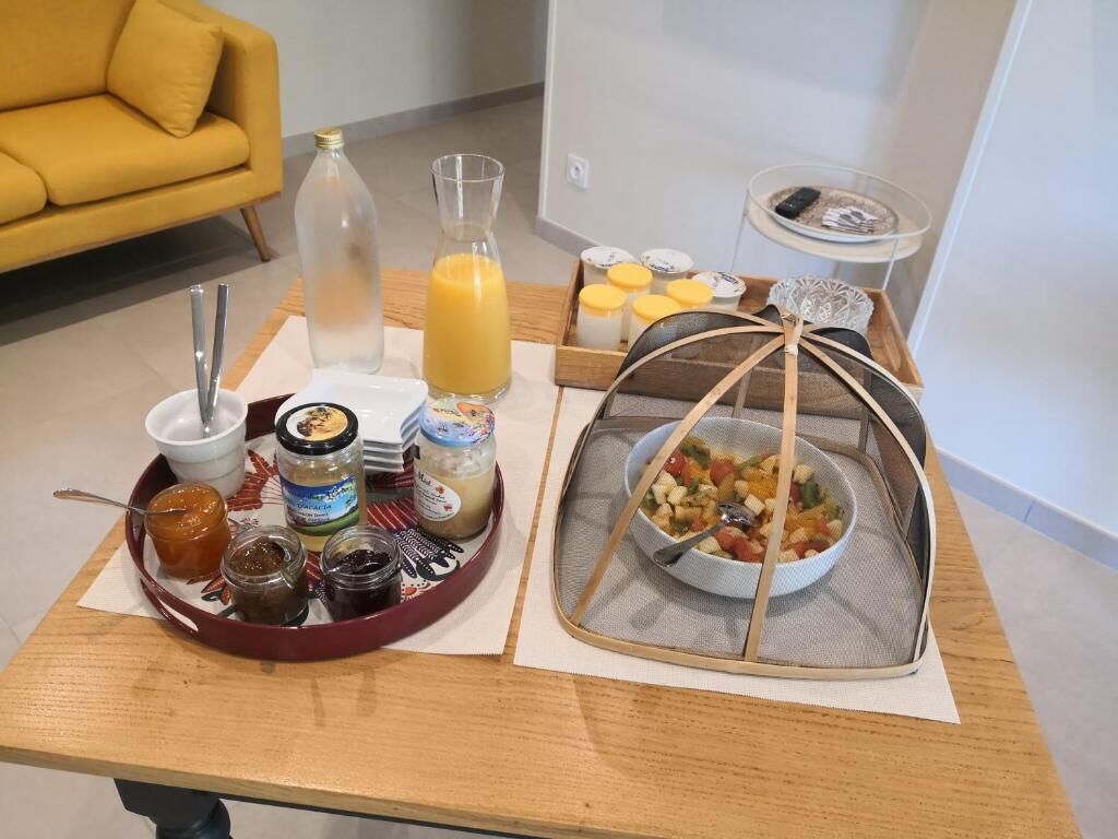 A breakfast tray with various condiments, a glass of orange juice, and a bowl of cereal.