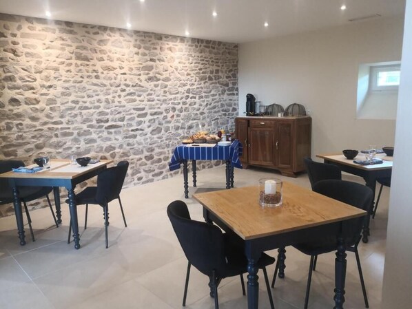 A dining area with stone walls, wooden tables, and black chairs. - La Maison de Bruno (Juliénas)