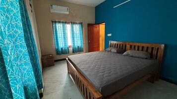 Een slaapkamer met een houten bed, een plafondventilator, een raam met gordijnen en een blauwe muur.