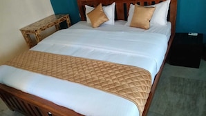 Ein ordentlich gemachtes Bett mit gesteppter Decke, einem Holzkopfende und zwei Nachttischen.