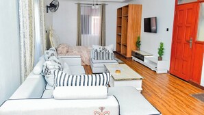 Un salon moderne avec un canapé d’angle, une table basse et un téléviseur fixé au mur.