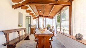 Un comedor rústico con una mesa de madera, bancos y suelo de piedra.