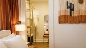 Una habitación de hotel con una cama, una lámpara, un perchero para bata y un adorno de pared.