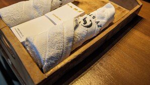 A wooden tray with two towels and a box on a wooden countertop in a bathroom. - King Suite with Balcony and Bathtub near UN Nairobi, Cozy Stead Garden House (Nairobi)