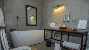 A modern bathroom with a bathtub, toilet, sink, and mirror. - King Suite with Balcony and Bathtub near UN Nairobi, Cozy Stead Garden House (Nairobi)