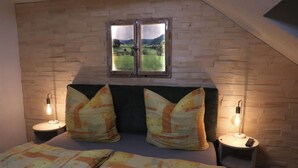 Een slaapkamer met een houten hoofdeinde, twee bedlampen en een raam met uitzicht op een landschap.