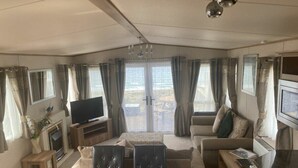 Ein gemütliches Wohnzimmer mit Sofa, Fernseher, Kamin und Essbereich mit Tisch und Stühlen.