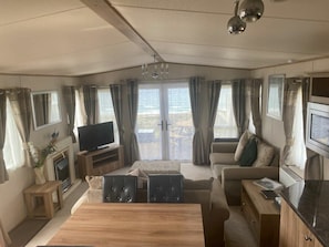 Una sala de estar acogedora con un sofá, televisor, chimenea y comedor con mesa y sillas.