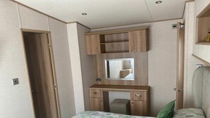 Ein kleines Schlafzimmer mit Bett, Schreibtisch, Spiegel und Kleiderschrank.