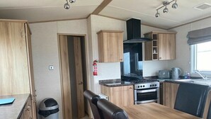 Eine kleine Küche mit Holzschränken, einem Gasherd und einem Spülbecken.