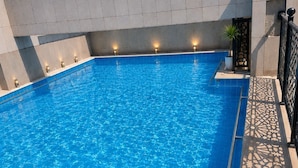 Una piscina con acqua cristallina e blu, circondata da un bordo piastrellato e un muretto.