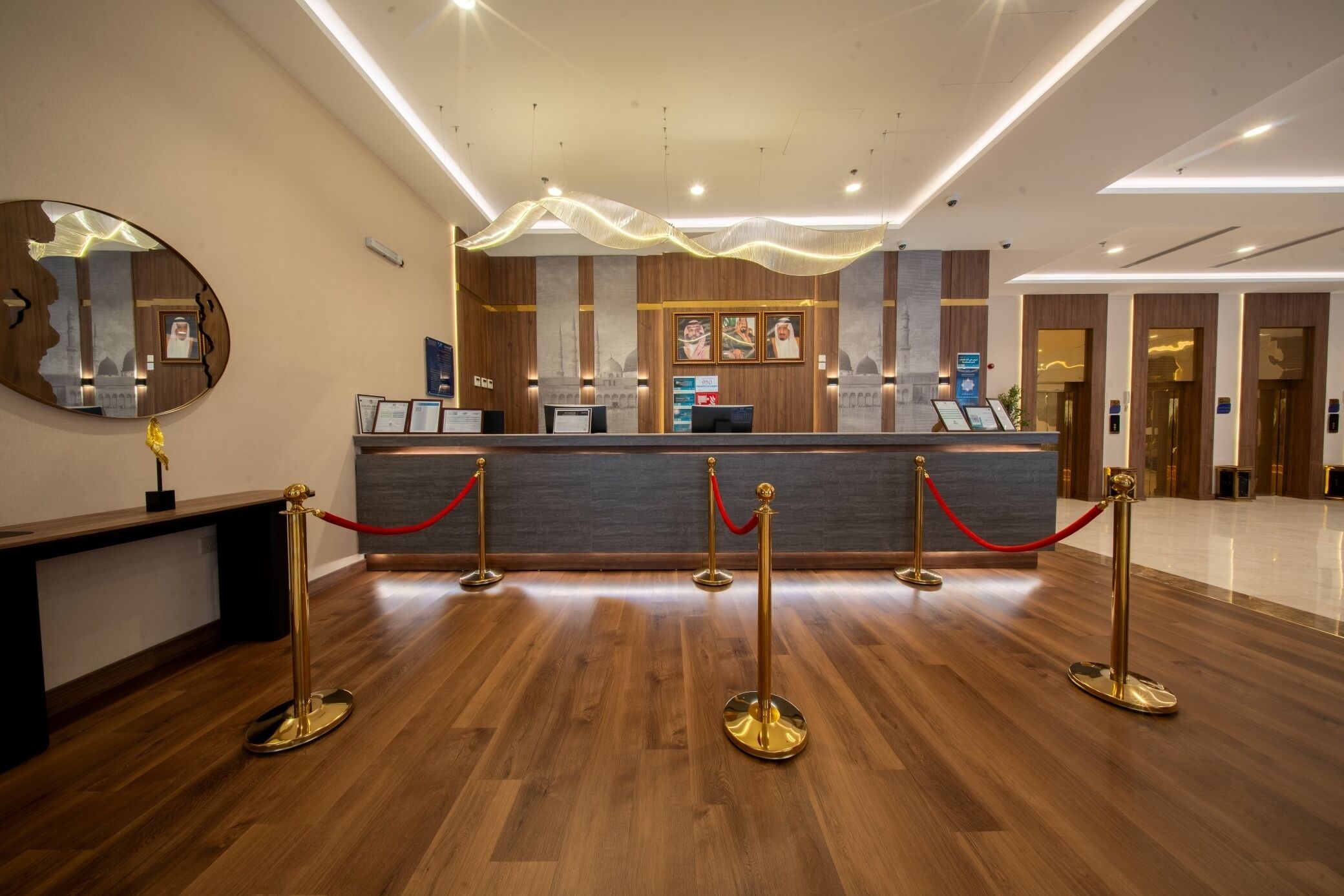 A reception desk with a modern design, a wooden floor, and a red rope barrier.