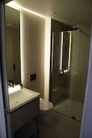 Uma casa de banho moderna com cabine de duche em vidro, lavatório branco e sanita.
