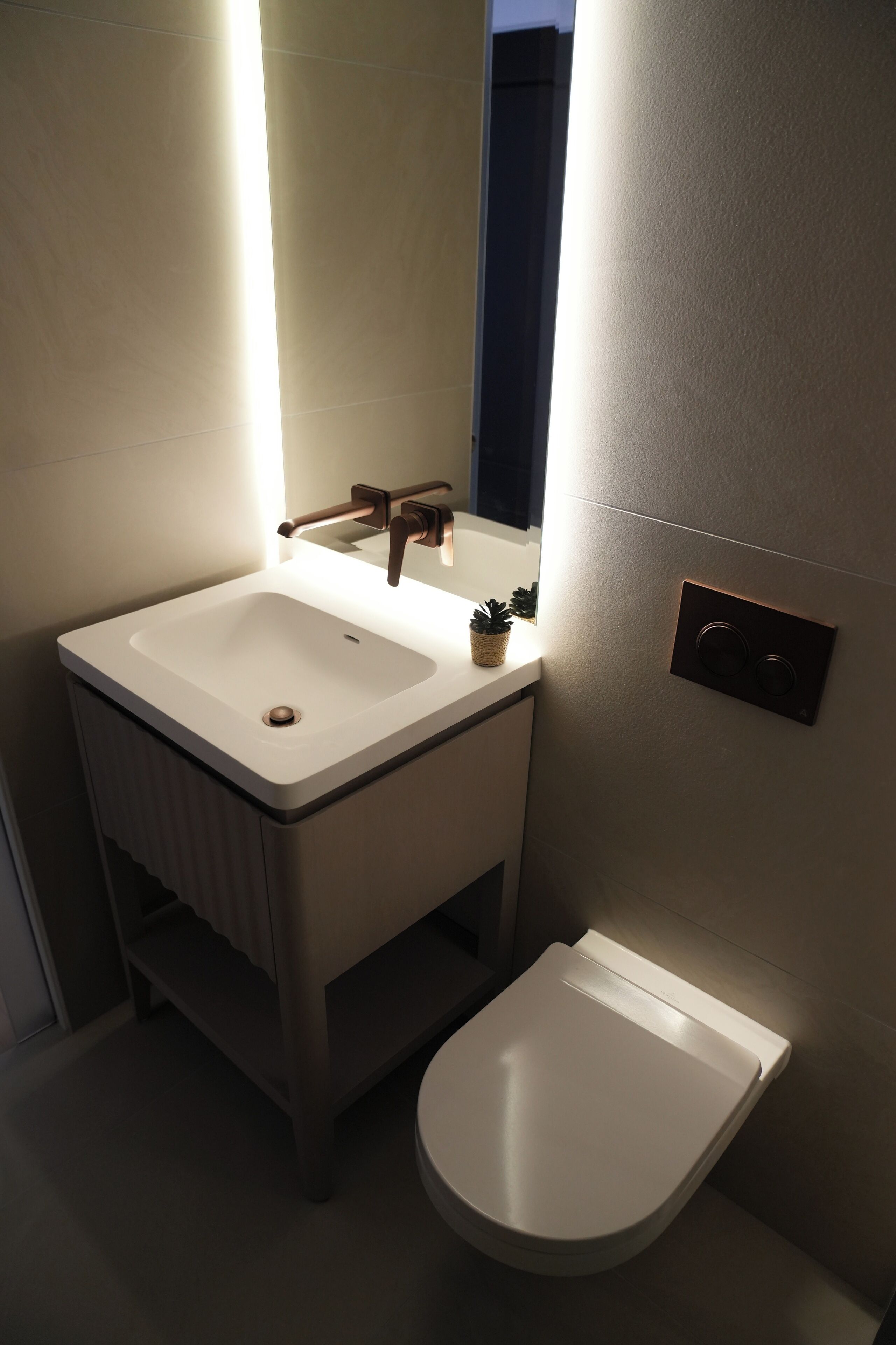 A bathroom with a white sink, a mirror, a toilet, and a light fixture.