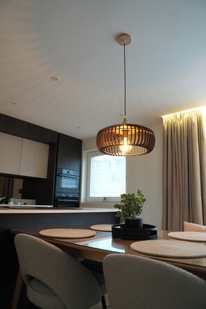 A modern kitchen with a central island, pendant lighting, and a potted plant. - 1st Floor Luxury 2-bed Apt, Sleeps 6 (St. Andrews)