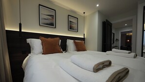 A hotel room with a large bed, two pillows, a headboard, and two framed pictures on the wall. - 1st Floor Luxury 2-bed Apt, Sleeps 6 (St. Andrews)