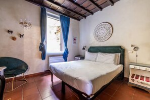 Un dormitorio con cama, una silla, un escritorio, una araña y un adorno en la pared.