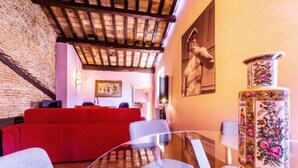 A modern living room with a red sofa, a glass coffee table, and a decorative vase. - Welcome in charming loft in Campo dè Fiori (Roma)