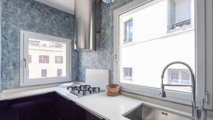 A modern kitchen with a gas stove, a stainless steel sink, and a window overlooking a building. - Welcome in charming loft in Campo dè Fiori (Roma)