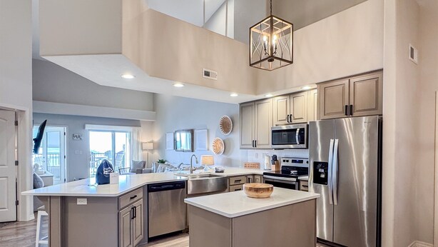 A modern kitchen with a central island, stainless steel appliances, and a view to the outside. - Heavenly Pointe | Penthouse Lake Views, Elevator, Accessible, King Beds (Branson)