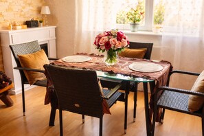 Un comedor con mesa de vidrio, individuales tejidos y sillas con cojines.