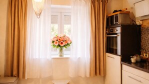 A kitchen with wooden cabinets, a microwave, and a small table with a vase of flowers. - Village house in a quiet location, green oasis vacation home (Hefersweiler)