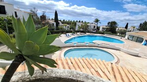 A swimming pool with a curved edge, surrounded by lounge chairs and a stone deck. - Rafael BeachGarden (Albufeira)
