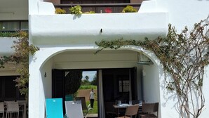 A two-story building with a covered outdoor seating area, a small garden, and a clear sky. - Rafael BeachGarden (Albufeira)