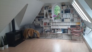 Un estadi tranquil·l amb llar de foc, prestatges de llibres, una finestra amb vistes i una cadira moderna.