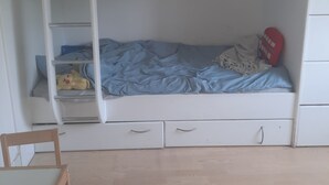 Un llit superposat amb una escala, una petita estant i un joguet al llit de dalt.
