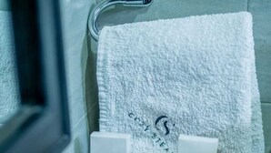 A bathroom with a white towel, a small wooden tray with two rolled towels, and a bottle of shampoo. - Spacious Junior Suite near UN Nairobi, Cozy Stead Garden House (Nairobi)