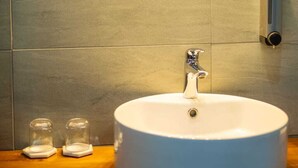 A bathroom with a round white sink, a chrome faucet, and a wall-mounted light fixture above the sink. - Spacious Junior Suite near UN Nairobi, Cozy Stead Garden House (Nairobi)