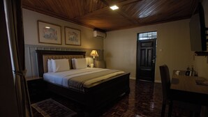 A hotel room with a wooden ceiling, a bed with white linens, a bedside table, a lamp, and a door leading to another room. - Spacious Junior Suite near UN Nairobi, Cozy Stead Garden House (Nairobi)