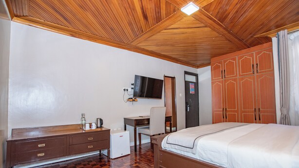 A bedroom with a wooden ceiling, a bed, a desk, a chair, and a wardrobe. - Spacious Junior Suite near UN Nairobi, Cozy Stead Garden House (Nairobi)